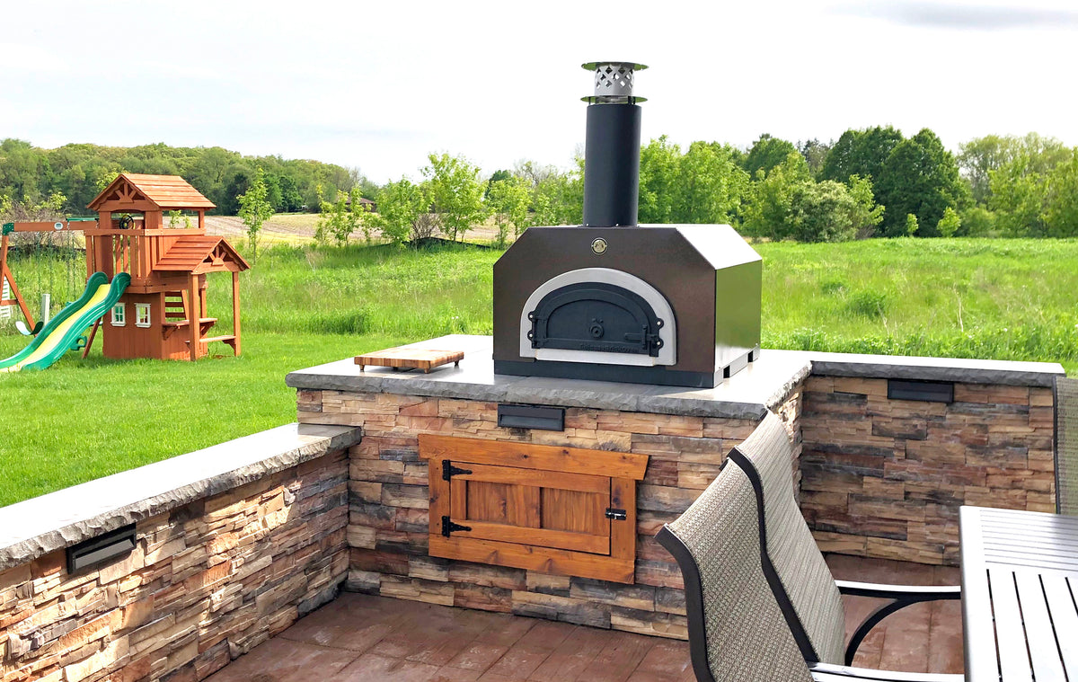 Copper Vein 750 Countertop oven in a stone outdoor kitchen overlooking a garden