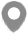 A simple gray map pin icon with a drop-like shape and a circular hole in the center, used to indicate a specific location or point of interest on a map. The icon has a minimalistic and flat design with no additional details.