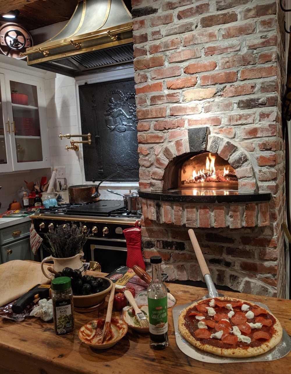 Wood-fired brick pizza oven built into a home kitchen beside a range.