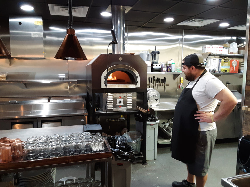 Chef beside a Chicago Brick Oven Hybrid in a restaurant kitchen