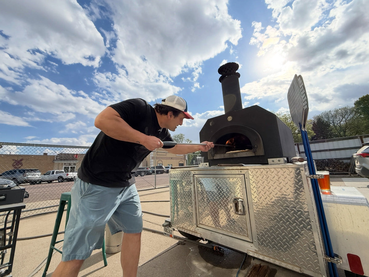 Cooking with a CBO Tailgater pizza oven mounted on its aluminum trailer