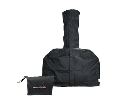 A heavy-duty all-weather cover with a tall central chimney section stands upright. Beside it, there is a smaller black bag with the logo and text "Chicago Brick Oven." The cover appears to be designed for Chicago Brick Oven’s CBO countertop ovens.