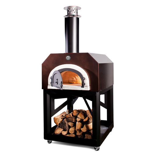 The CBO 750 Mobile Stand by Chicago Brick Oven is a large, high-performance wood-fired pizza oven perched on a black metal frame with an underneath compartment filled with stacked firewood. This remarkable outdoor oven, featuring a front opening and a chimney, glows warmly inside as it bakes a loaf of bread to perfection.