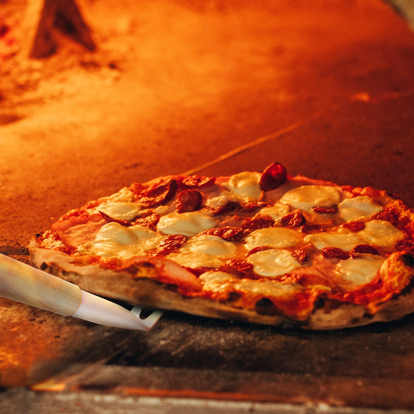 A freshly baked pizza with bubbling cheese and slices of pepperoni is being expertly turned and removed from a quality pizza oven using the Chicago Brick Oven Aluminum 17.5 inch Pizza Spinner Turning Fork with Wooden Handle and Leather Strap. The warm, golden glow from the oven highlights the crispy crust, making the pizza look incredibly appetizing.